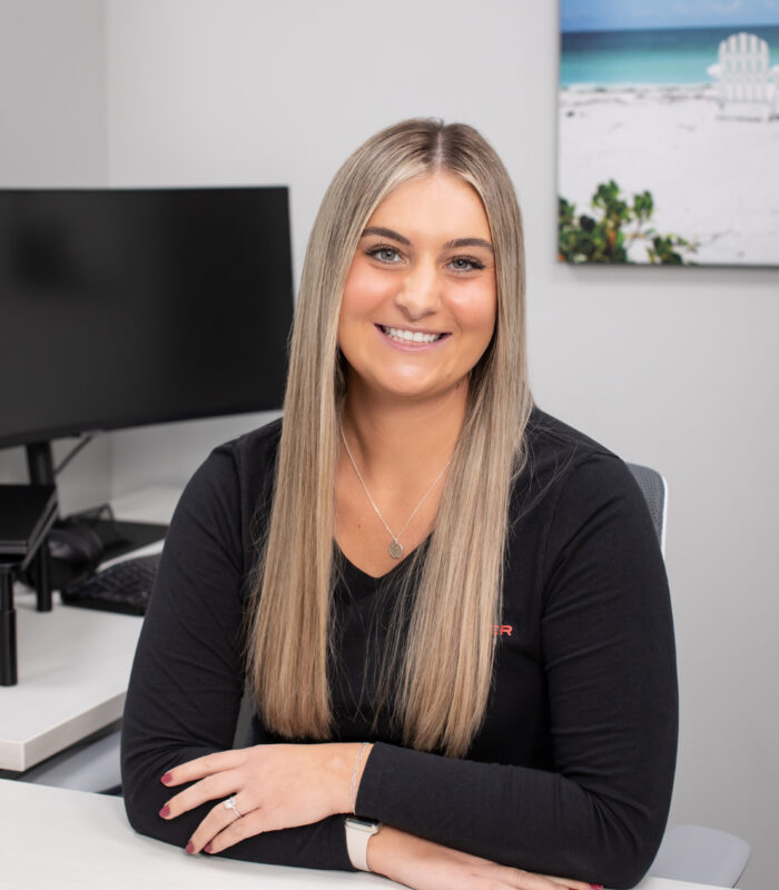 Meet Our Team - Professional and Welcoming Group at a Conference Table Faces the Camera, Team Leader Sitting on the Table with Arms Folded