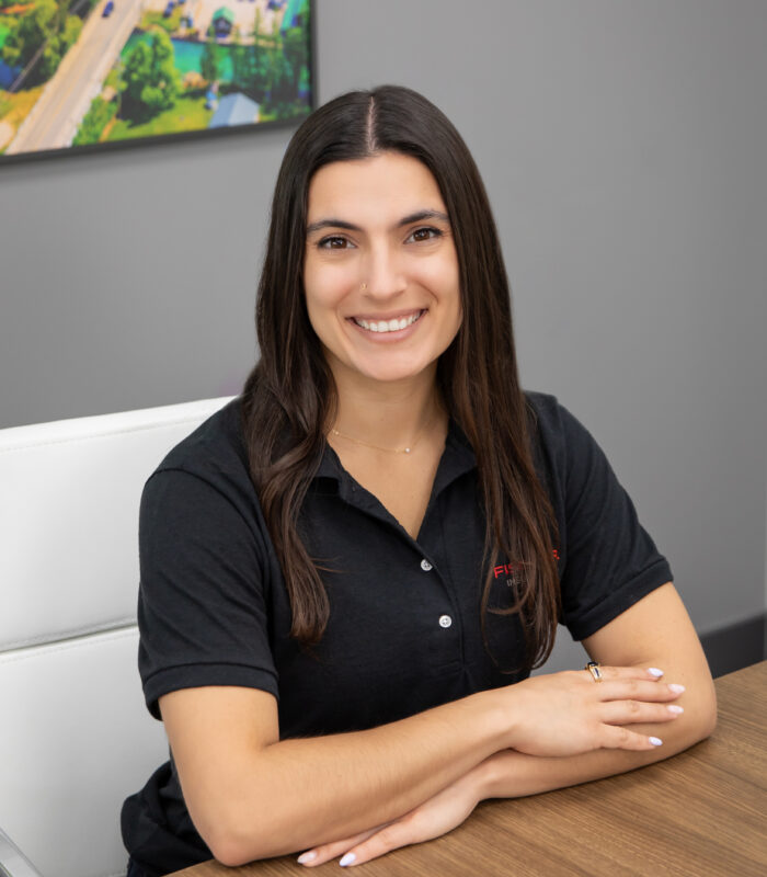 Meet Our Team - Professional and Welcoming Group at a Conference Table Faces the Camera, Team Leader Sitting on the Table with Arms Folded